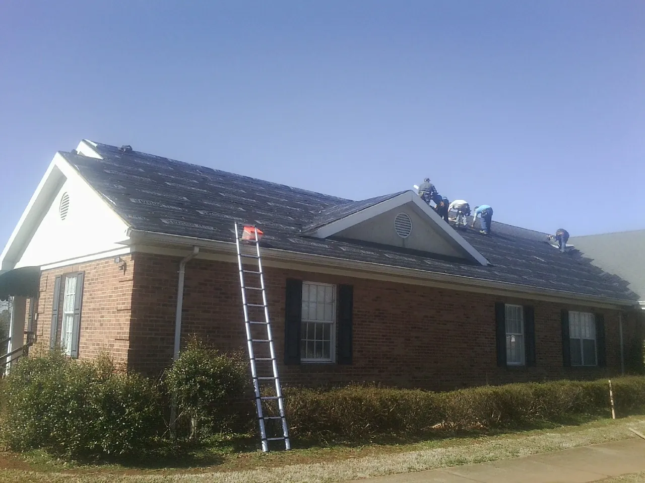 Crew tearing shingles off a brick ranch roof with a ladder set — Metal Roof Repair work by our crew in Ridgefield Park