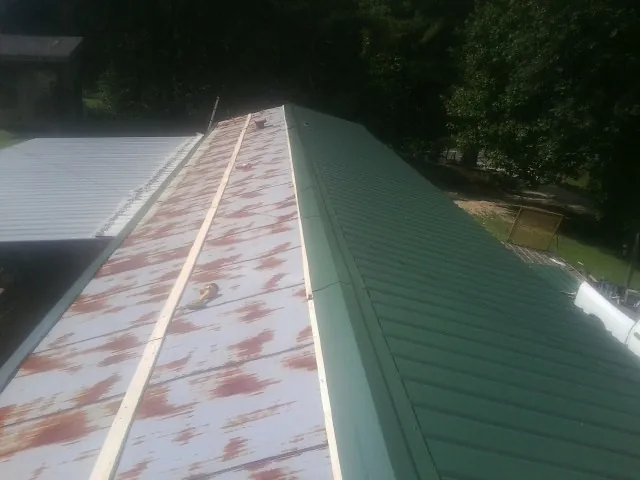 Old rusted panels beside newly installed green metal roofing — Wind Damage Roof Repair by Roofing Brothers in Ridgefield Park