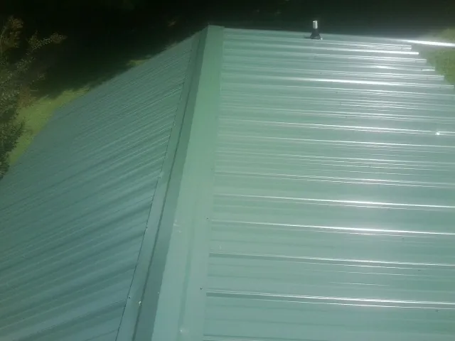 New green metal panels meeting at the ridge of a roof — Flat Roof Repair work by our crew in Ridgefield Park
