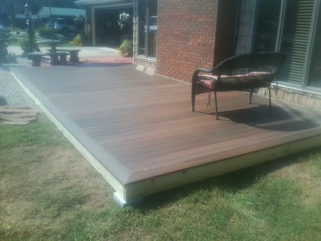 New wood deck and wicker chair beside a brick house in Ridgefield Park