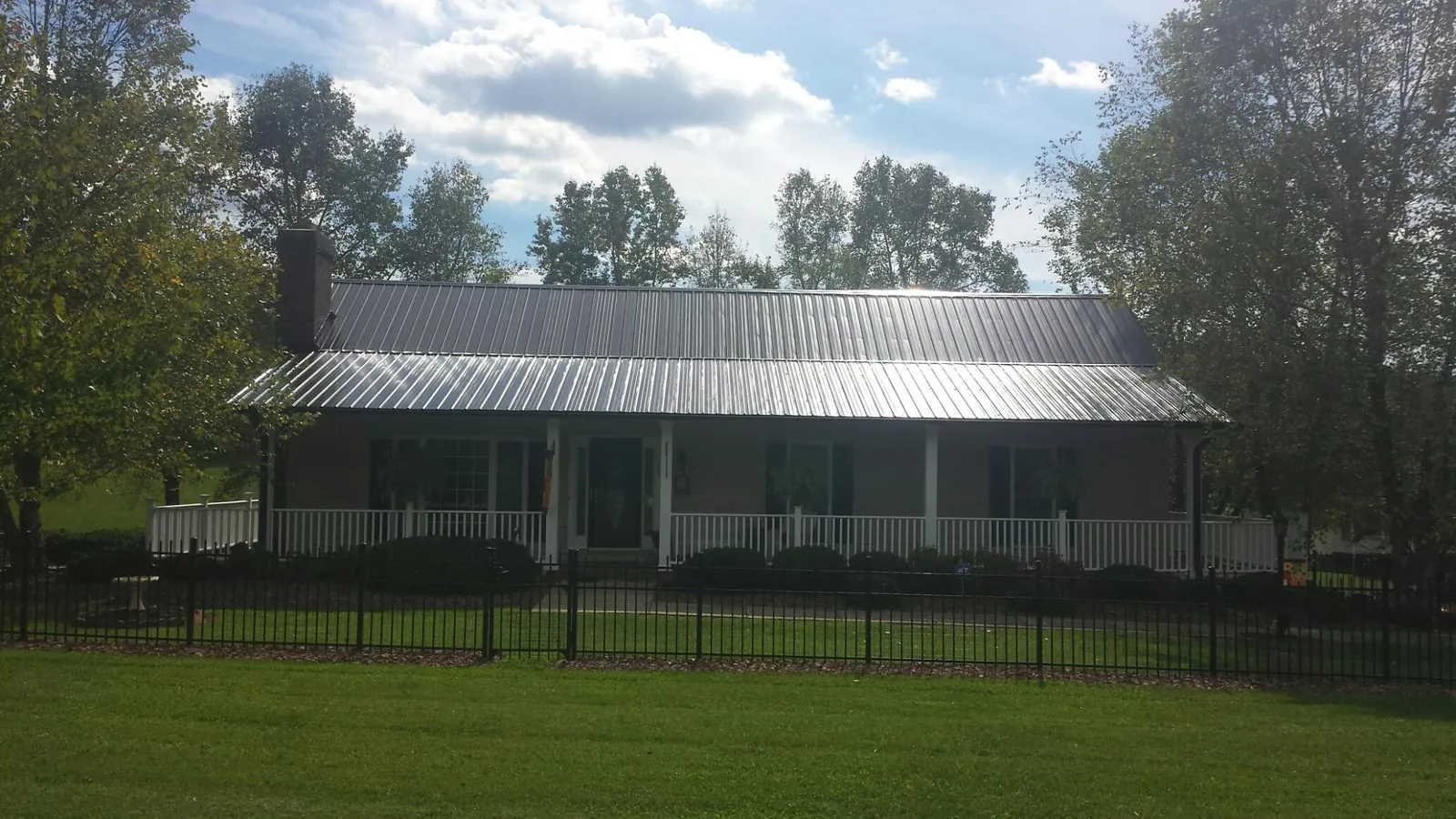 Gray metal roof on a brick ranch with a full width front porch — Gutter Guard Installation work by our crew in Ridgefield Park