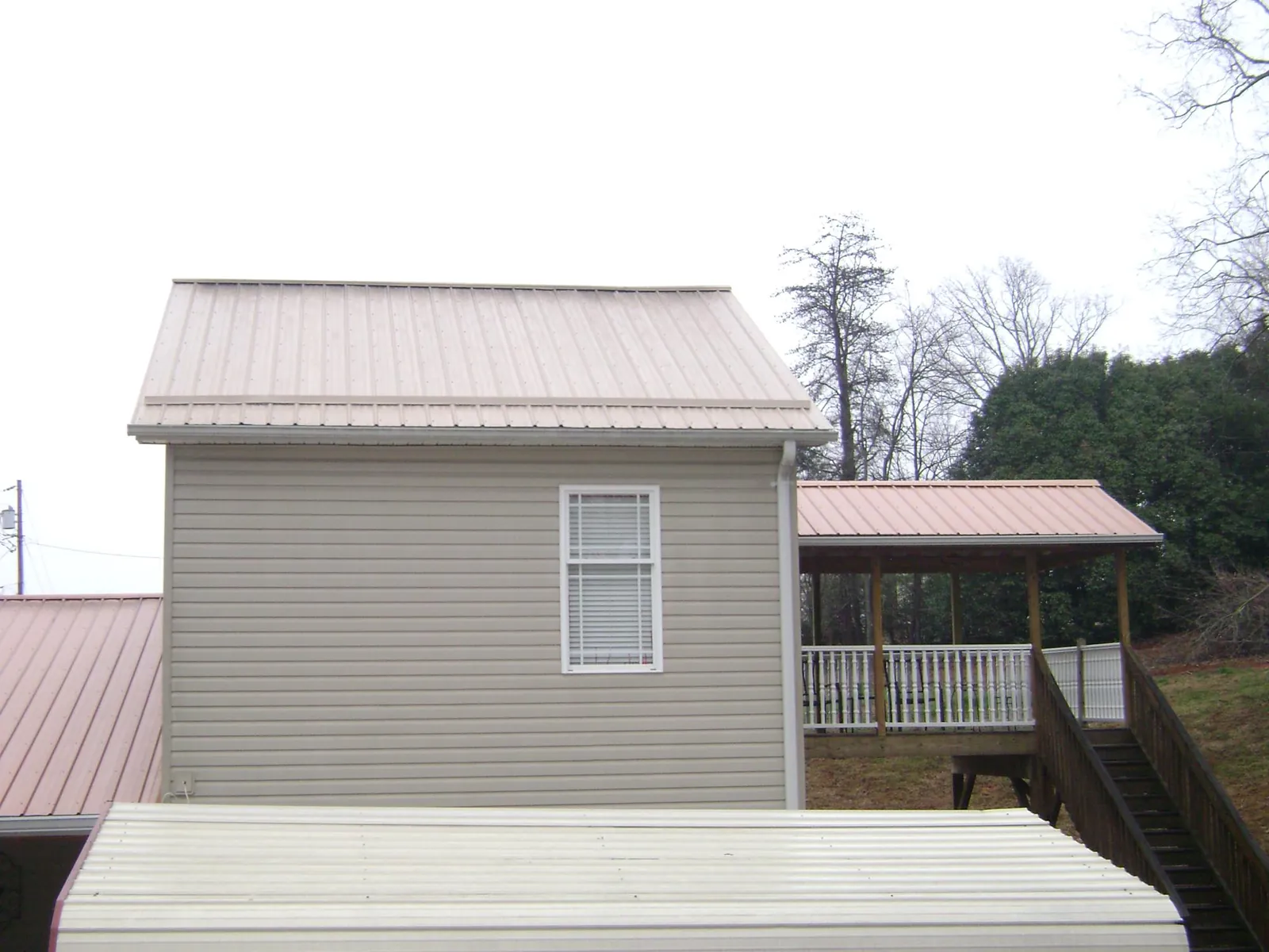 Tan metal roofs on a two story addition and attached porch, from a Roof Replacement job in Ridgefield Park