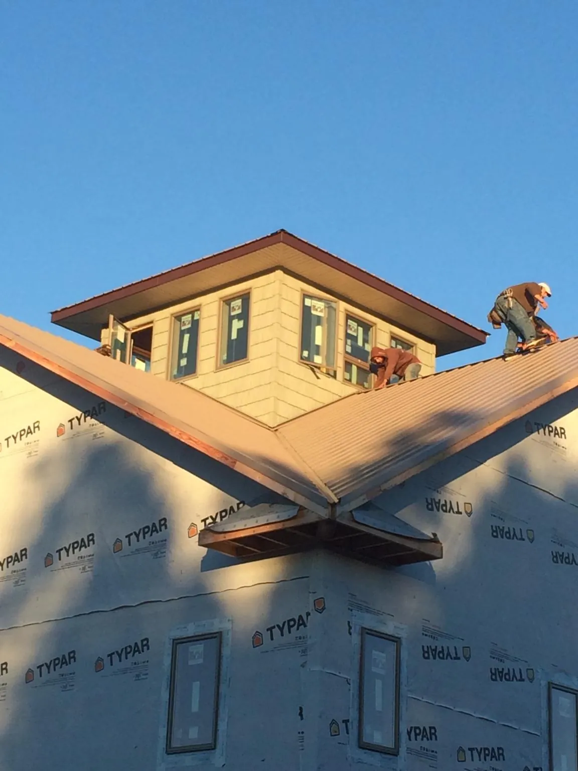 Roofers working around a rooftop cupola on a new metal roof at sunset — Roof Waterproofing in Ridgefield Park by Roofing Brothers